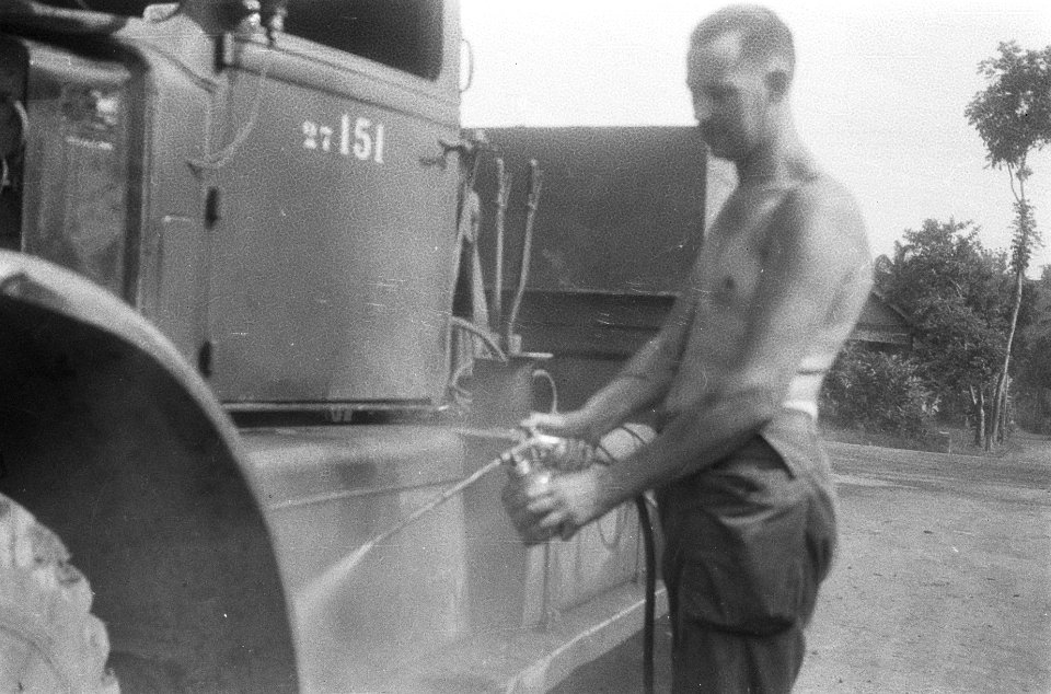 Een chauffeur bewerkt met een verfspuit de wielkast van zijn vrachtwagen, Bestanddeelnr 411-1-1