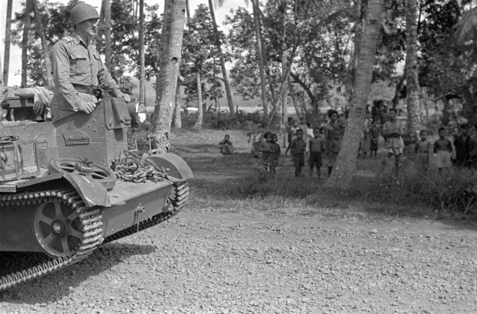 Een brencarrier passeert een kampong. Voorop staat een Nederlandse officier. D…, Bestanddeelnr 821