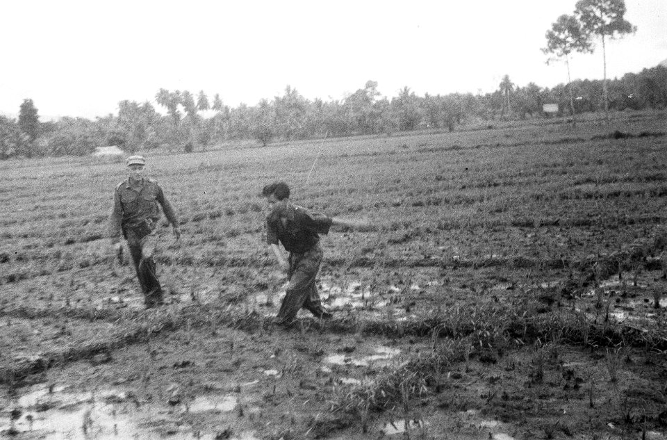 Een Indonesische militair komt uit een rijstveld. De Nederlandse militair links,, Bestanddeelnr 5357