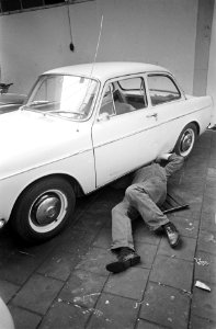 Een automonteur is onder een auto gekropen, Bestanddeelnr 921-7199