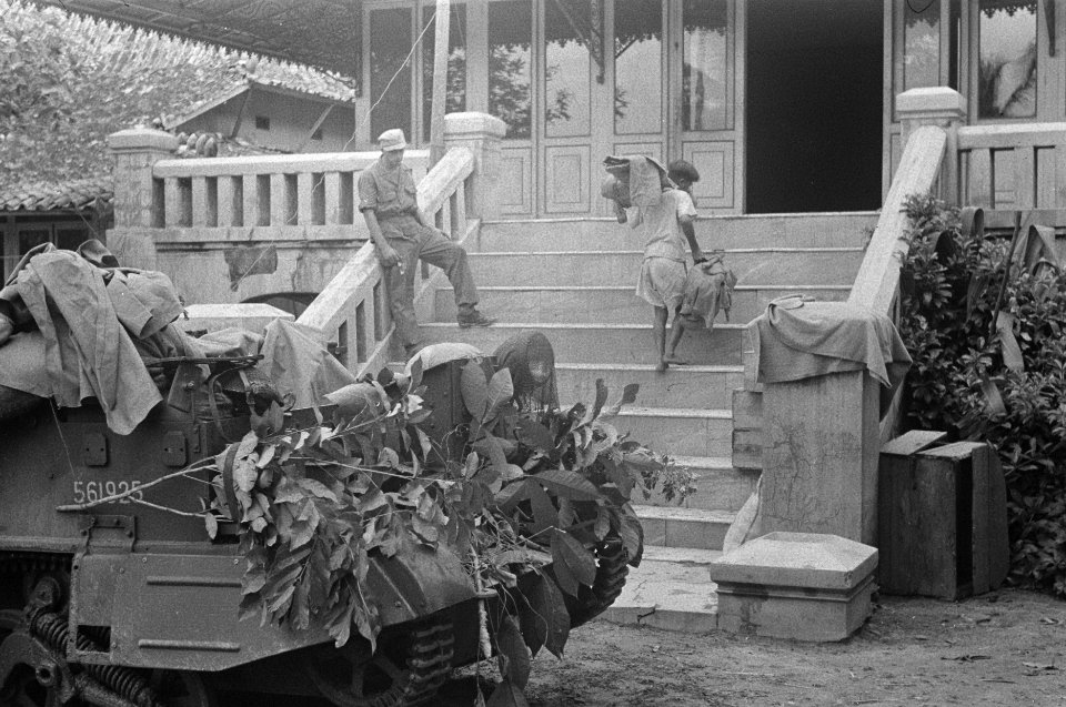Een Indonesische jongen tilt voorwerpen een de trappen van een koloniaal huis o…, Bestanddeelnr 348-4-5