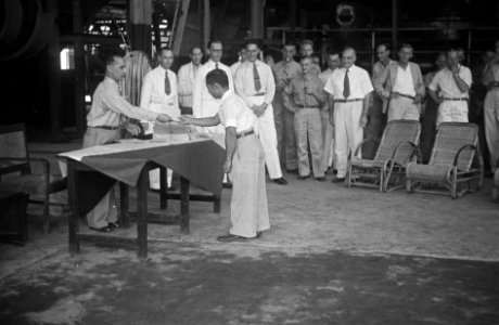 Een Indonesische man krijgt iets uitgereikt (een diploma) van een man in unifor, Bestanddeelnr 7095