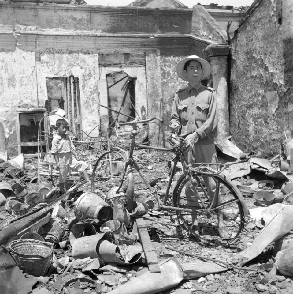 Een Indonesiër met een fiets in een ruïne van een winkel in Bandoeng, Bestanddeelnr 255-8321
