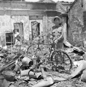 Een Indonesiër met een fiets in een ruïne van een winkel in Bandoeng, Bestanddeelnr 255-8321