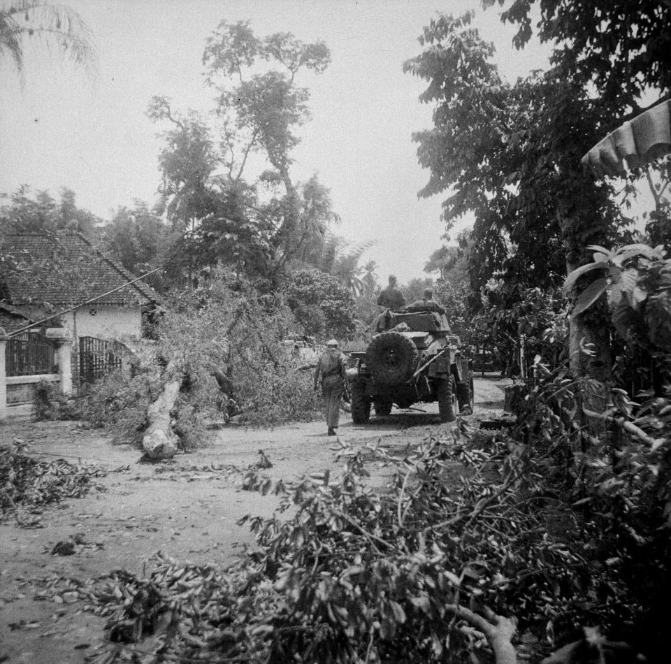 Een Humber pantserwagen rijdt over een weg langs een huis en een omgehakte boom, Bestanddeelnr 15106