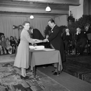 Fabrieksdirecteur Jan van Abbe (rechts) overhandigt document aan vrouw, Bestanddeelnr 255-8561