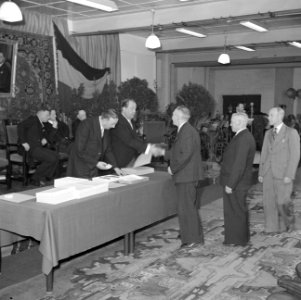 Fabrieksdirecteur Jan van Abbe (achter de tafel) schudt hand van een man tijdens, Bestanddeelnr 255-8496
