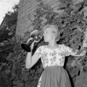 Erika Klein poseert met glas moezelwijn voor een muur begroeid met druiven, Bestanddeelnr 254-4639