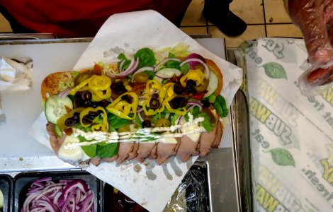 Food service worker preparing a submarine sandwich at Subway