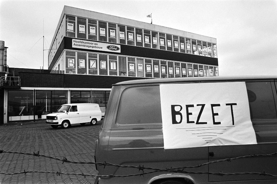 Fordfabriek in Amsterdam weer bezet door het personeel ivm een dreigende sluiting busje voor de fabriek met doek me Bezet erop, Bestanddeelnr 931-5634