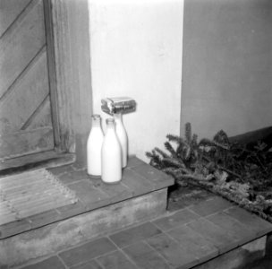 Flessen melk en pakjes boter staan op de stoep bij de voordeur, Bestanddeelnr 252-8731