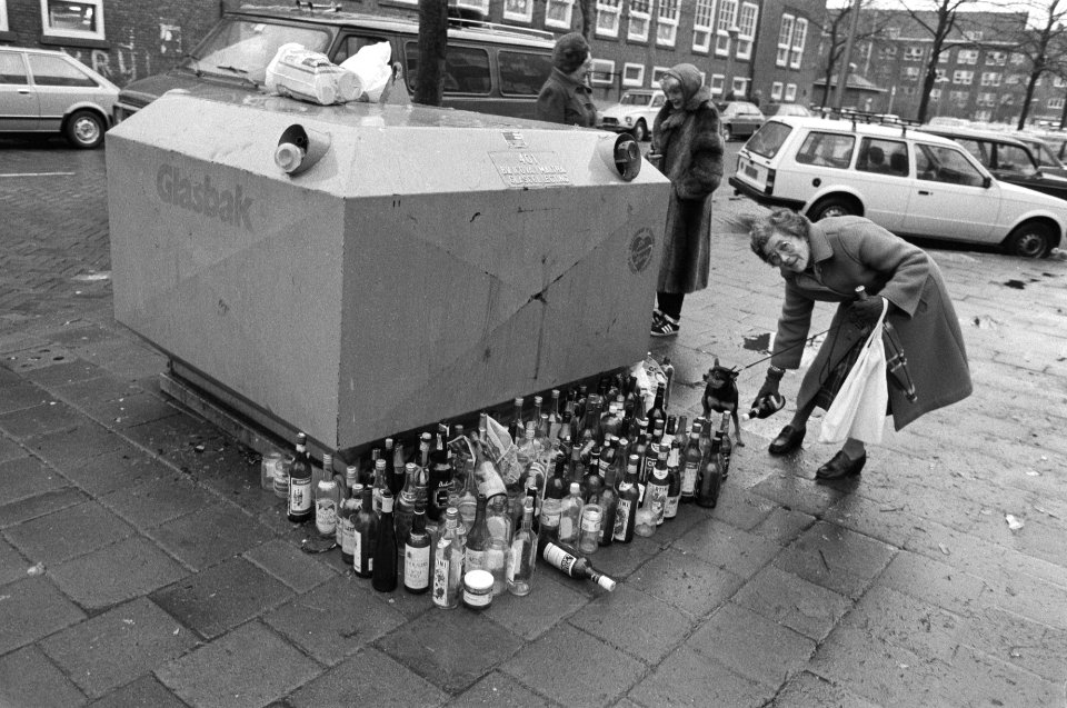 Flessen naast volle glasbak na feestdagen. In Amsterdam vrouw fles naast de voll, Bestanddeelnr 931-8915