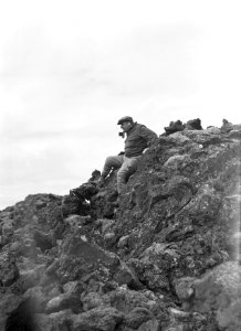 Fotograaf Willem van de Poll verlaat met het fototoestel in de mond een lavarots, Bestanddeelnr 190-0283