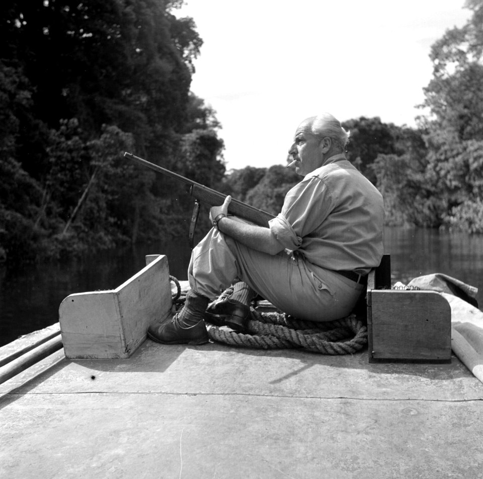 Fotograaf Willem van de Poll met een geweer op de boeg van een korjaal op de Cop, Bestanddeelnr 252-5654