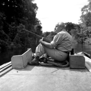 Fotograaf Willem van de Poll met een geweer op de boeg van een korjaal op de Cop, Bestanddeelnr 252-5654