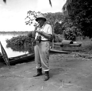 Fotograaf Willem van de Poll een banaan etend in Suriname, Bestanddeelnr 252-6710