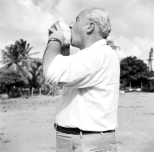 Fotograaf Willem van de Poll drinkt uit een kokosnoot op plantage San Juan van H, Bestanddeelnr 252-7536