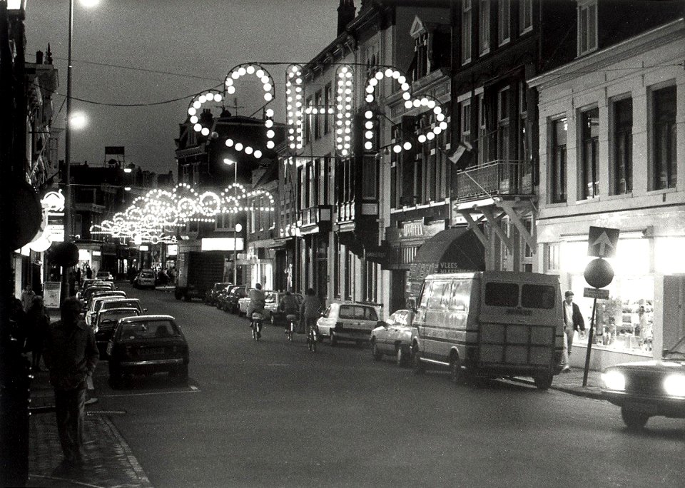Feestverlichting in de Kruisstraat z.n.h. zuiden. Zie ook 54-015564. Aangekocht in 1988 van United Photos de Boer bv. - Negatiefnummer 25775 k 22 a. - Gepubliceerd in het Haarlems Dagblad van 05-11-19