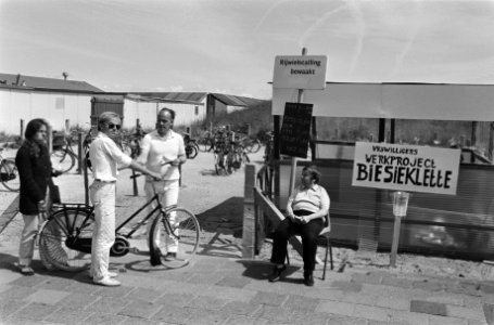 Fietser bij de stalling met het bord Vrijwilligers werkproject Biesieklette, Bestanddeelnr 932-6539