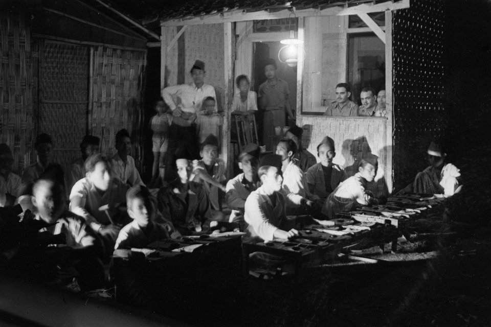 Gamelan-orkest bij avond. In een soort loge kijkten twee militairen toe, Bestanddeelnr 2134