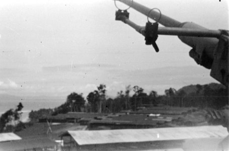 Gezicht over een baai, daarvoor een heuvel met hangars en loodsen. Rechts de loo, Bestanddeelnr 5769