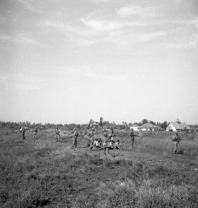 Gevangentransport. Een groep gevangenen zit op de grond, bewaakt door soldaten, Bestanddeelnr 15866