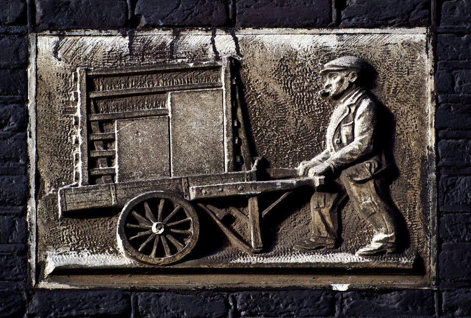 Gevelsteen Driehoekstraat, afbeelding van een man die een kar duwt