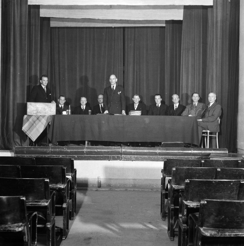Geen beschrijving Aantal heren achter een bestuurstafel op een podium, Bestanddeelnr 900-9711