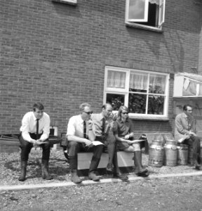 Gebouwen, huizen, melkbussen, mannen, vrouwen, zitten, Bestanddeelnr 253-6210