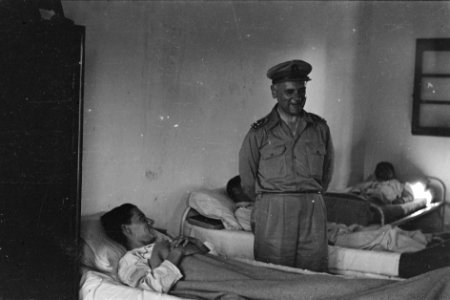 Generaal Kruls in gesprek met een patiënt in een militair hospitaal, Bestanddeelnr 4192