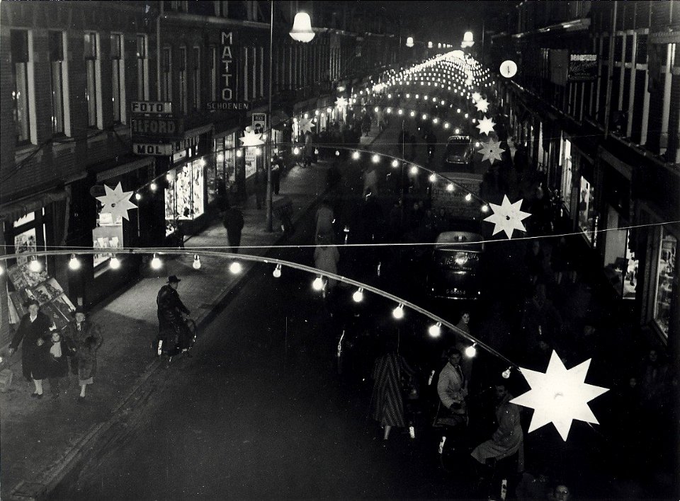 Generaal Cronjéstraat, tijdens de kerst weken, bij avond versierd en verlicht. Aangekocht in 1977 van fotograaf C. de Boer. Identificatienummer 54-004350, NL-HlmNHA 54010752