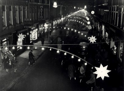 Generaal Cronjéstraat, tijdens de kerst weken, bij avond versierd en verlicht. Aangekocht in 1977 van fotograaf C. de Boer. Identificatienummer 54-004350, NL-HlmNHA 54010752