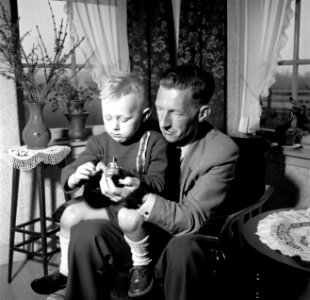 Gerard met zijn vierjarig zoontje Gerrie op schoot met een speelgoed helikopter., Bestanddeelnr 254-3308