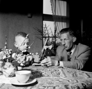 Gerard met zijn vierjarig zoontje Gerrie aan tafel met een speelgoedhijskraan, Bestanddeelnr 254-3305