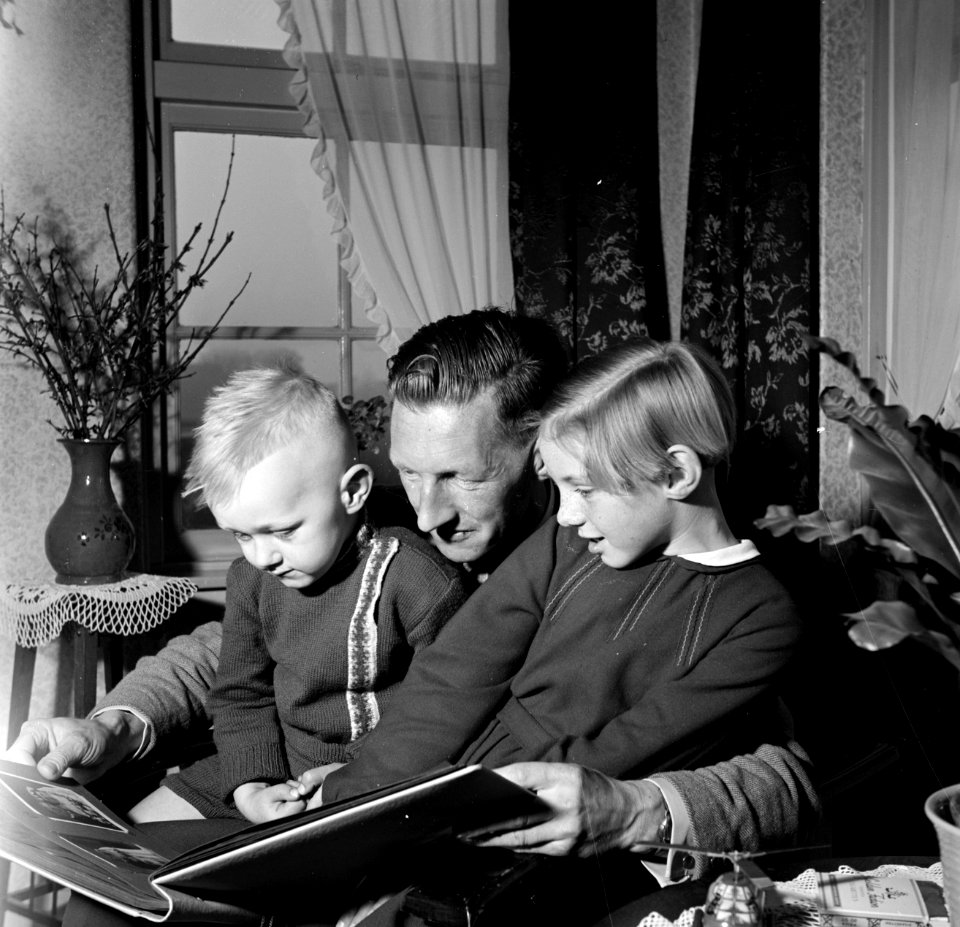 Gerard met zijn beide kinderen Gerrie en Marietje op schoot terwijl ze een fotoa, Bestanddeelnr 254-3309