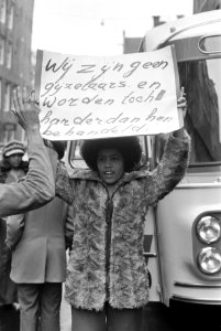Gemeenteraad van Amsterdam behandelt begroting 1975 Surinamer met protestbord, Bestanddeelnr 927-5507