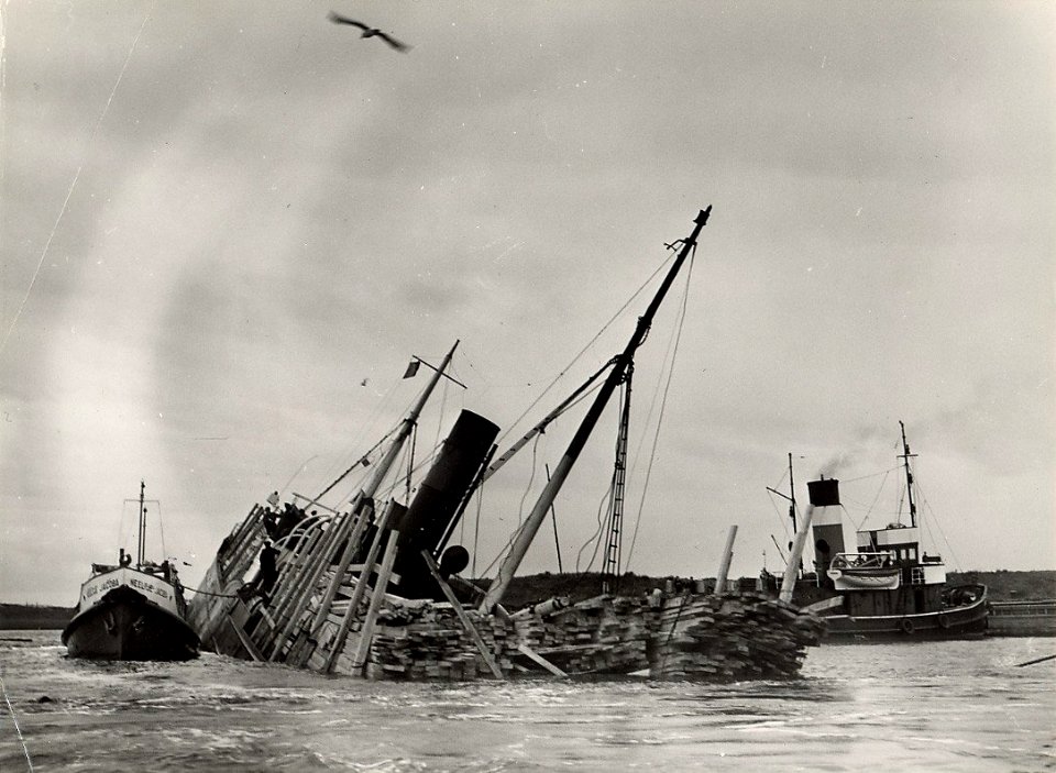 Halfgezonken met hout geladen vrachtboot in de Averij- of Bijleggershaven te IJmuiden afbeelding door C.de Boer. - 1949.10.23. - 1 foto 17,9x24,3 cm. Afgebeeld is de Zweedse houtboot Ketty, die in de 
