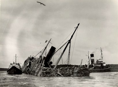 Halfgezonken met hout geladen vrachtboot in de Averij- of Bijleggershaven te IJmuiden afbeelding door C.de Boer. - 1949.10.23. - 1 foto 17,9x24,3 cm. Afgebeeld is de Zweedse houtboot Ketty, die in de 