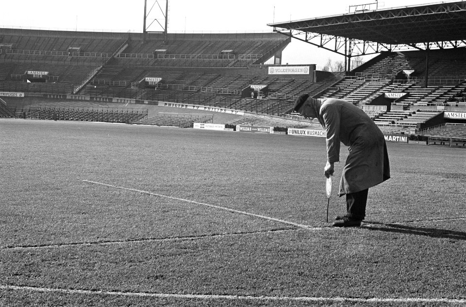 Grasmat in Olympisch Stadion weer groen. De terreinknecht prikt met staaf in gra, Bestanddeelnr 914-9047