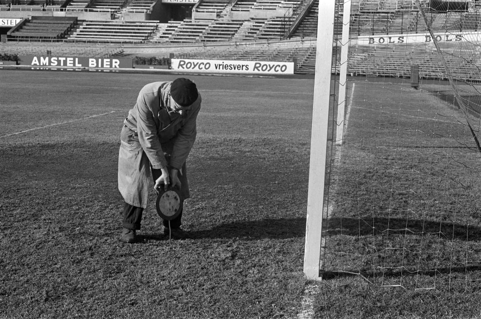 Grasmat in Olympisch Stadion weer groen. De terreinknecht prikt met staaf in gra, Bestanddeelnr 914-9049