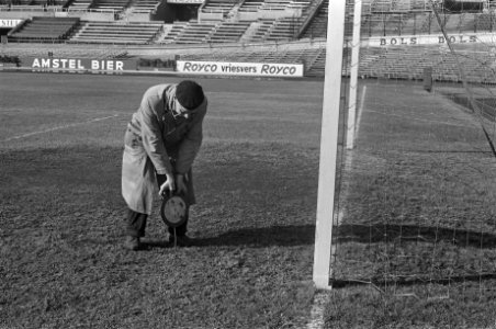 Grasmat in Olympisch Stadion weer groen. De terreinknecht prikt met staaf in gra, Bestanddeelnr 914-9049