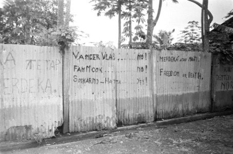 Graffiti op schutting van golfplaten Tetap Merdeka. Van der Vlas ....No Fan Mo, Bestanddeelnr 3082