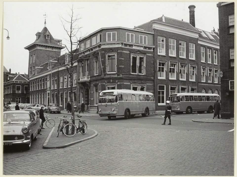 Grafische inrichting Joh. Enschedé en Zn. aan het Klokhuisplein hoek Damstraat, met NZH bussen en verkeersagent. NL-HlmNHA 54004420
