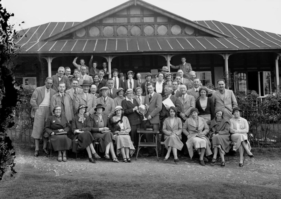 Group of golfers outside Llandrindod Wells Golf Club pavilion, one being presented with a cup (1293772)