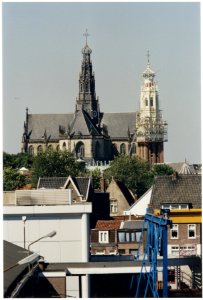 Grote-of St. Bavokerk ziende vanuit het oosten. Op de voorgrond de toren van de Bakenesserkerk nog gedeeltelijk in de steigers na een opknapbeurt. NL-HlmNHA 54036285