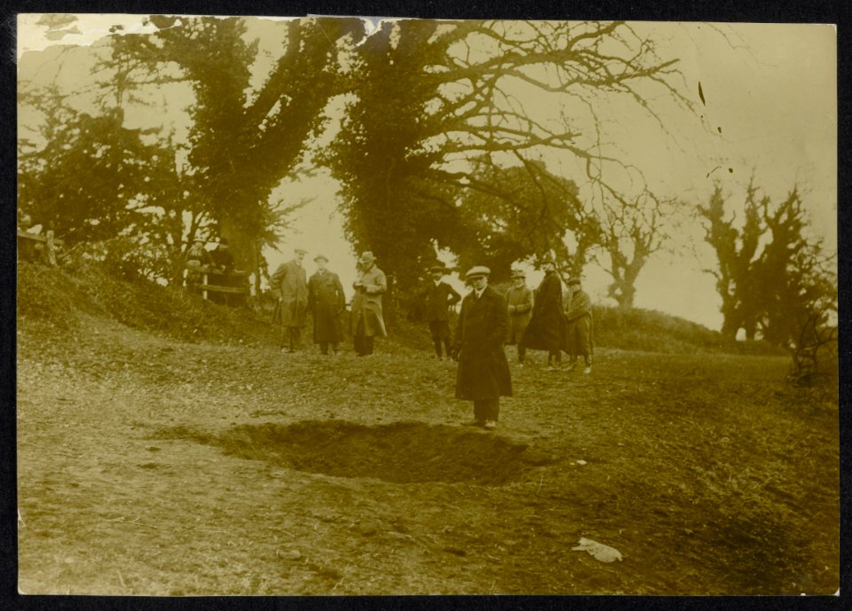 Groep burgers bekijkt een krater tussen de bomen van een bos., Bestanddeelnr 158-1299