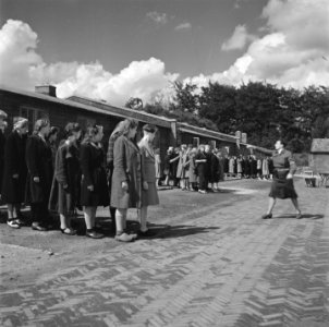 Groepen vrouwen staan aangetreden op een appelplaats Een kampbewaardster geeft , Bestanddeelnr 900-4805