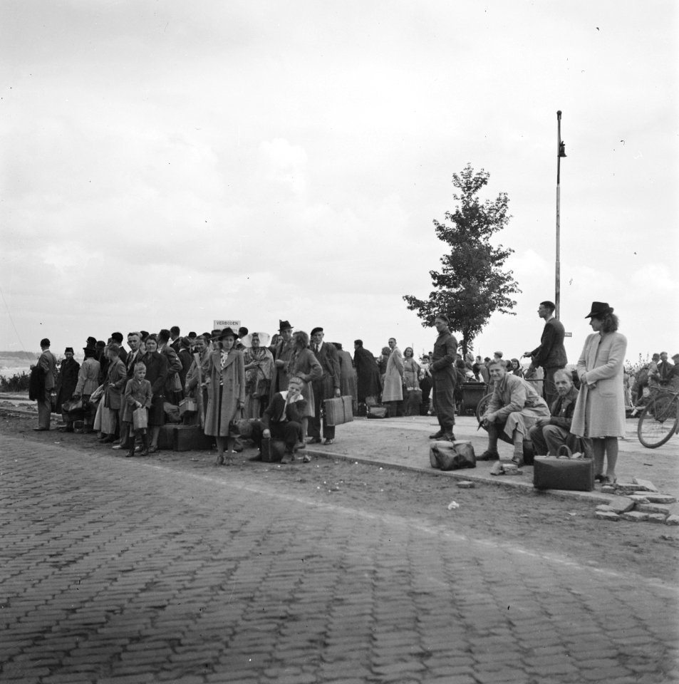Grote groep mensen met bagage langs een weg, Bestanddeelnr 900-6025