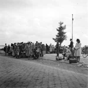Grote groep mensen met bagage langs een weg, Bestanddeelnr 900-6025