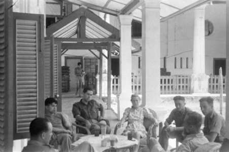 Groep geuniformeerde mannen en een vrouw zitten op een veranda, Bestanddeelnr 52-6-4